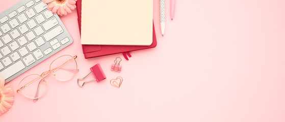 Wall Mural - Office supplies on pastel pink background. Flat lay notebooks, pencils, glasses, and keyboard. Education, art concept
