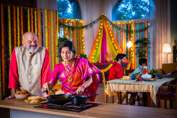 Indian senior old happy couple cooking food for diwali festival celebration at home