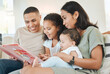 © peopleimages.com - Parents, children and story book on couch in home with smile, reading and listening for bonding in living room. Father, mother and daughter with baby, happy and connection at family house in Colombia