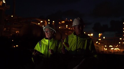 Wall Mural - Team Engineer working at night shift with laptop Inside Oil Refinery Gas Chemical plant. Senior Engineer wearing safety jacket and PPE working about Petrochemica Chemical Prodiction 