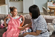 © Cavan Images - African American woman and daughter try on new dresses
