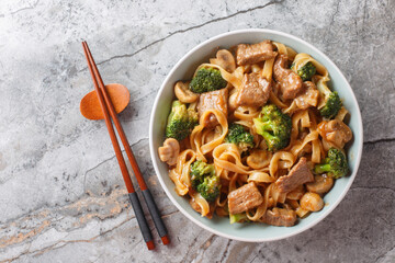 Poster - Beef teriyaki, noodles, mushrooms and broccoli stir fry close-up in a bowl on the table. Horizontal top view from above