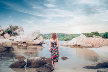 woman on beautiful beach with rocks watching sunset