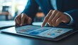 © TigerDude - Businessman using a tablet to showcase a financial graph and data on the screen with a pointing finger,
