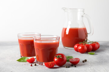 Canvas Print - Tasty tomato juice in glasses, jug, basil, peppercorns and fresh vegetables on light grey table