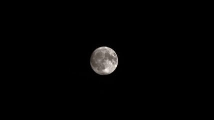 full moon covered by clouds in the sky at dark night