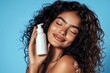 © Zaleman - Young girl holding blank shampoo bottle and conditioner for hair on blue background, smiling woman portrait, bodycare concept of moisturizing spa