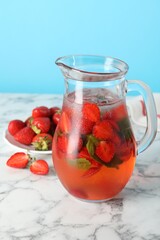 Poster - Tasty strawberry lemonade with mint in jug and berries on white marble table against light blue background