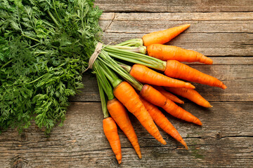 Wall Mural - Bunch of tasty ripe juicy carrots on wooden table, top view