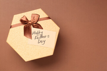 Poster - Card with phrase Happy Father's Day and gift box on light brown background, top view. Space for text