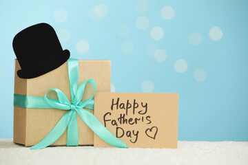 Sticker - Greeting card with phrase Happy Father's Day, gift box and paper hat on light table