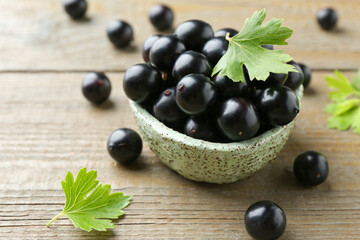 Wall Mural - Fresh ripe black currant berries and leaves on wooden table, closeup