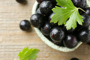 Wall Mural - Fresh ripe black currant berries and leaves on wooden table, closeup