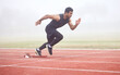 Outdoor, sports and man running at track for fitness, exercise and training for competition. Fog, mist and Asian male athlete with speed at athletics field for cardio, workout and practice for race