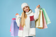 © Prostock-studio - Winter sales. Positive young girl in winter hat holding colorful shopping bags, yellow background