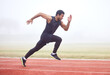 © Nina2024/peopleimages.com - Outdoor, fitness and man running at track for sports, exercise and practice for competition. Fog, mist and Asian male athlete with speed at athletics field for workout, cardio and training for race