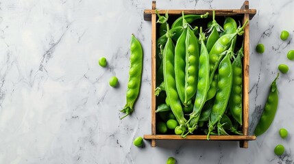 Canvas Print - Fresh peas displayed on marble background in wooden box viewed from above