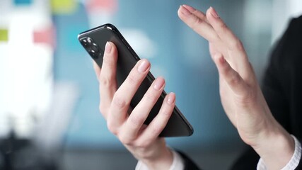 Businesswoman's hands using smartphone for communication in modern office. Woman engaging with phone for message, browsing or chatting online. Female professional connected with technology. Close up 