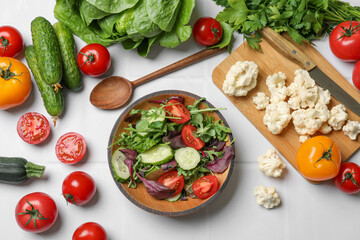 Wall Mural - Healthy vegetarian food. Salad in bowl and vegetables on white tiled table, flat lay