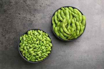 Raw green edamame soybeans and pods on grey table, top view