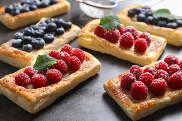 Wall Mural - Tasty puff pastries with berries on grey table, closeup