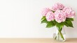 © Viktoriia Kan - Delicate white hydrangea blooms create a fresh, elegant display in a clear vase on a wooden table against a soft gray backdrop