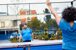 © Zoran Zeremski - Mixed adult couple playing padel on outdoor court.