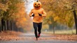 © fotogurmespb - Pumpkin-headed runner strides powerfully against the backdrop of strikingly colored fall foliage during a Halloween marathon