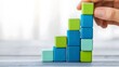 © F - Strategic business growth concept with hand placing green and blue blocks to build an upward graph representing success in marketing and sales. Business planning, and positive trends
