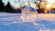 © Helois - A frozen soap bubble in snow with a sunset in the background.