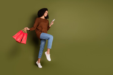 Sticker - Full length portrait of pretty young woman use phone walk empty space wear sweater isolated on khaki color background