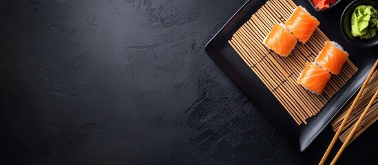 Aufkleber - Sushi plates accompanied by bamboo napkins on a black background with chopsticks copyspace template advertising