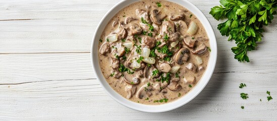 Fototapete - Homemade creamy beef stroganoff with mushroom slices and onions served in a bowl captured from above on white wood with copy space alongside Selective Focus Focus on the dish