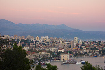 Wall Mural - Top view of the Croatian city of Split. Evening cityscape in the pink rays of the setting sun with mountains in the background.