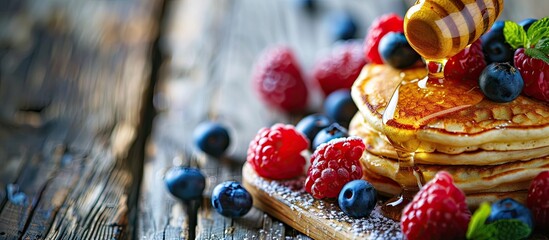 Fototapete - Small pancakes topped with berries and honey are featured in a close up on a wooden plate This represents pancake cereal and is part of breakfast food trends. with copy space image