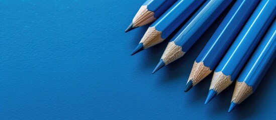 Wall Mural - Blue pencil among a group of pencils on a blue paper background Business concept. with copy space image. Place for adding text or design