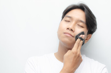 close-up young attractive asian man applying powder puff and cushion for facial makeup. young asian man in white tshirt doing makeup.