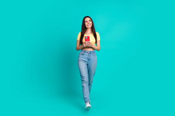 Wall Mural - Full body portrait of pretty young woman walk look empty space wear top isolated on turquoise color background