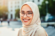 © Goffkein - Portrait of a beautiful satisfied cheerful rejoiced smiling young muslim woman wearing hijab and glasses outdoors
