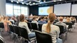 © Victoriia - Large group of people attending a business seminar in modern conference hall, focusing on speaker and presentation.