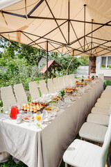 A summer tent with tables, food  and chairs on the wedding day