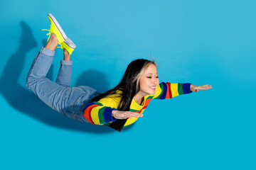 Canvas Print - Full size photo of pretty young girl flying enjoy flight wear trendy striped outfit isolated on blue color background