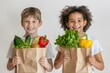 © Banstanks - Two smiling young children holding a paper grocery bag filled with fresh fruits and vegetables.