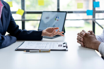 Two people are sitting at a table with a tablet and a piece of paper