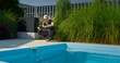 © StockMediaSeller - Technician working by the pool, checking a tablet while surrounded by greenery.