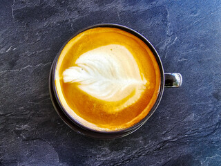 A cup of coffee latte top view with microfoam milk leaf shape foam closeup	