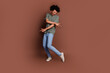© deagreez - Full body length photo of youth guy with wavy hair in gray t shirt and jeans dancing hip hop music isolated on brown color background