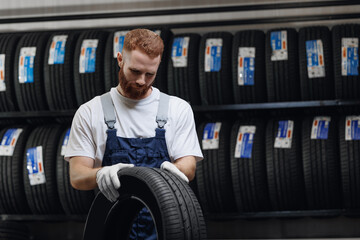 Wall Mural - Mechanic man holding new tire in store tyres