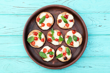 Wall Mural - Italian mini pizza . Aubergine (eggplant ) with mozzarella cheese and basil . On rustic background