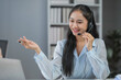 © amnaj - Asian customer service agent is smiling while speaking on a headset in her office